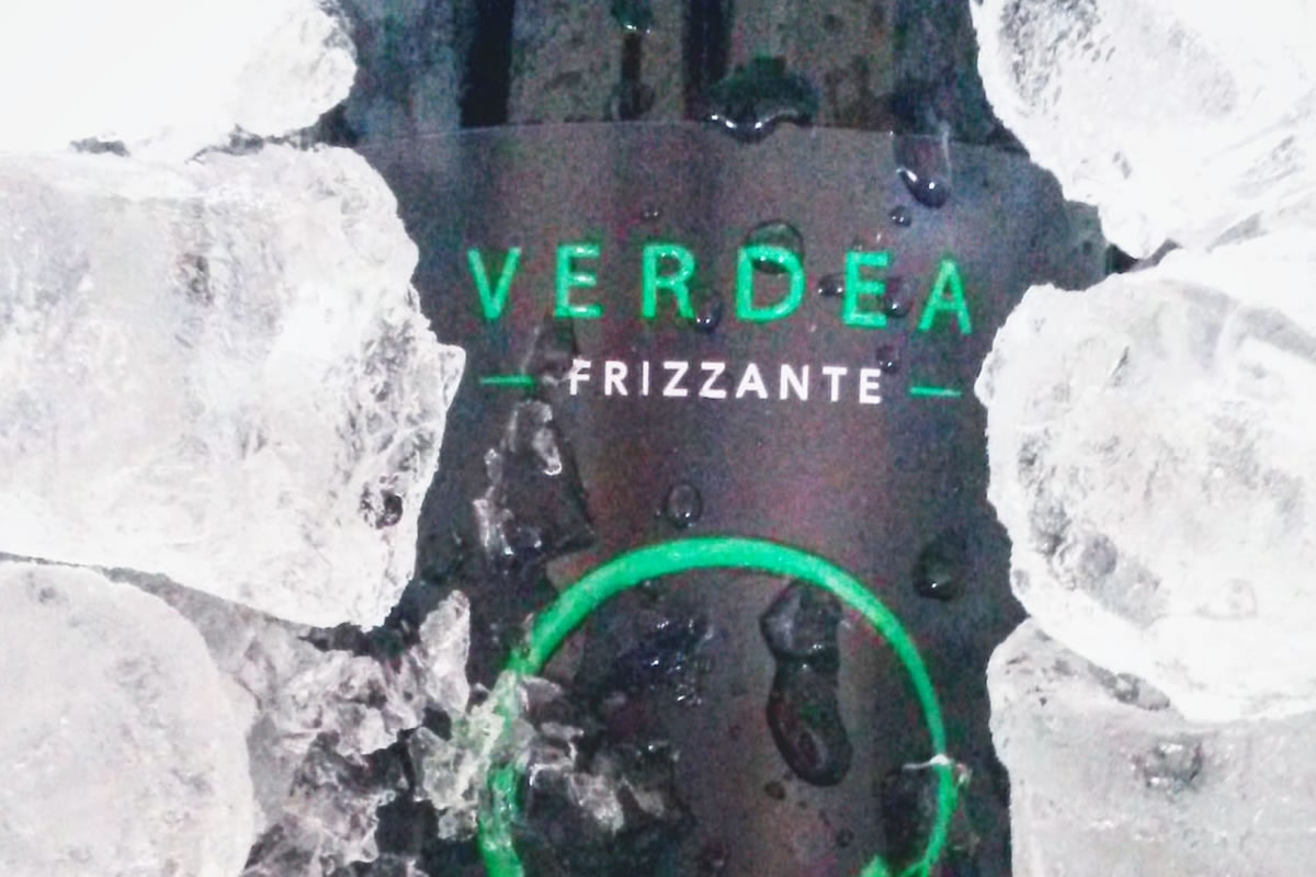 Bottiglia Verdea Frizzante in ghiaccio. Etichetta verde su sfondo nero, gocce d'acqua. Bevanda fresca e spumeggiante.